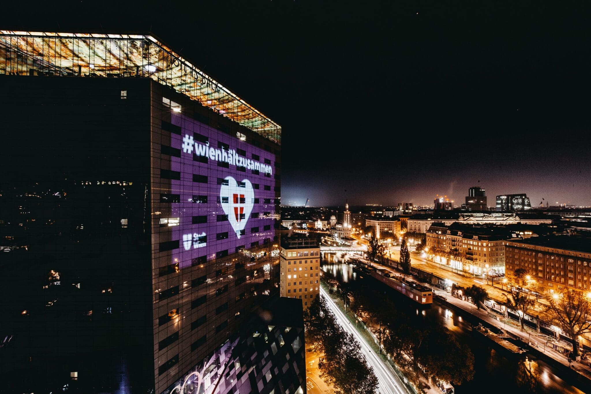 Nachtaufnahme mit Projektion auf Hochhaus "Wien hält zusammen".