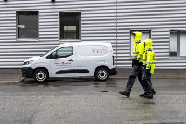 Lehrlinge in Schutzausrüstung vor einem Wiener Netze Auto