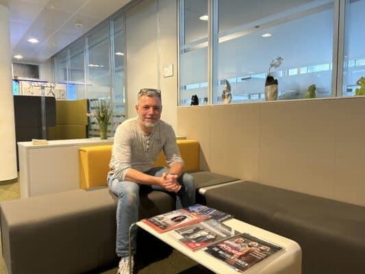 Alexander Förster sitzt im Büro vor einem Kaffeetisch mit Magazinen