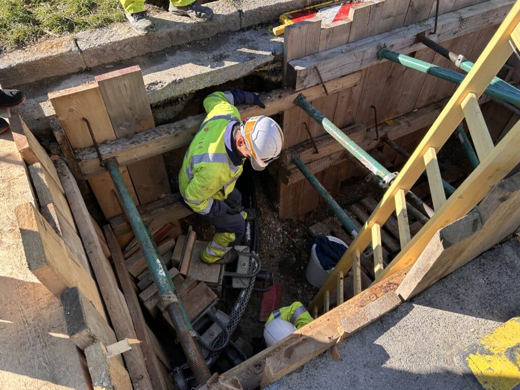 Arbeiter in Künette beim Kabeleinziehen